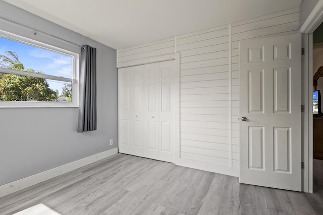 unfurnished bedroom featuring baseboards, wood finished floors, and a closet
