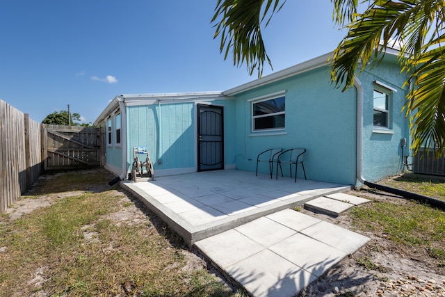 rear view of house featuring a gate, a patio, and a fenced backyard