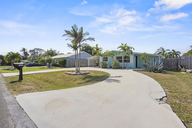 view of front facade featuring fence, a front yard, and curved driveway