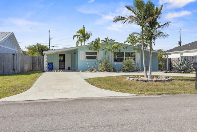 ranch-style house featuring a front yard, driveway, and fence