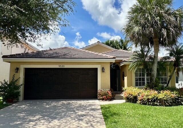 9530 Fox Trot Ln, Boca Raton, FL 33496 - ranch-style home featuring an attached garage, concrete driveway, stucco siding, and a tiled roof