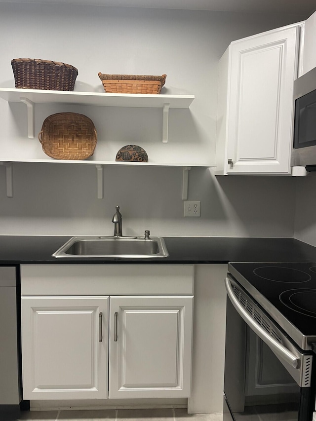 1432 S Lakeside Dr Unit 11, Lake Worth Beach, FL 33460 - kitchen with open shelves, dark countertops, white cabinetry, a sink, and appliances with stainless steel finishes