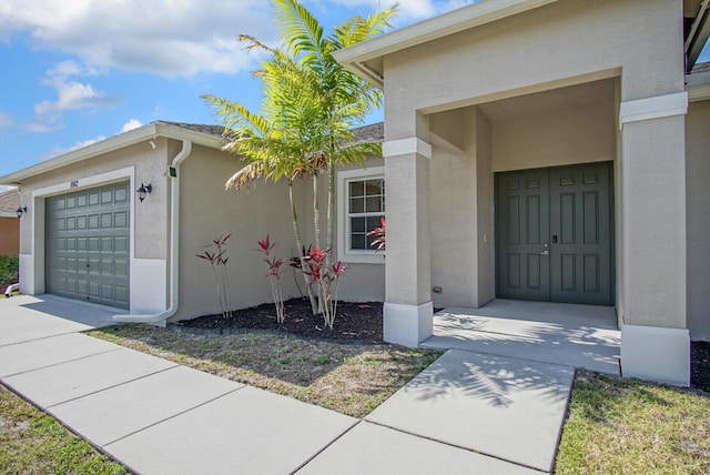 property entrance with stucco siding and a garage