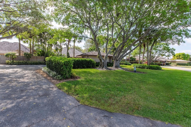 view of front of property with fence, aphalt driveway, and a front lawn