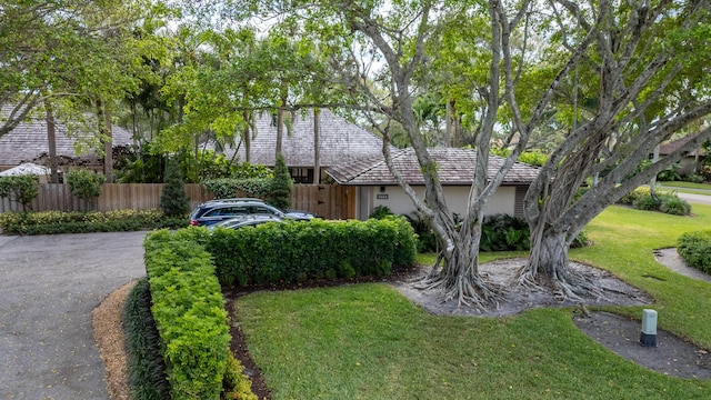 view of front of property featuring fence, a front lawn, driveway, and stucco siding