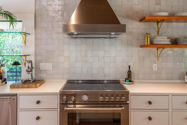 kitchen with high end stainless steel range oven, tasteful backsplash, open shelves, light countertops, and wall chimney exhaust hood