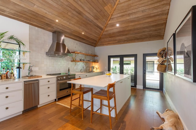 kitchen featuring a sink, high end range, wooden ceiling, wall chimney exhaust hood, and white cabinets
