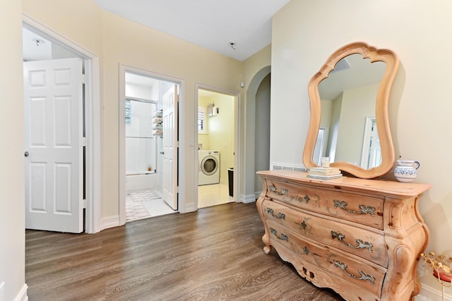 210 Via Villagio, Hypoluxo, FL 33462 - entrance foyer with washer / clothes dryer, arched walkways, baseboards, and wood finished floors