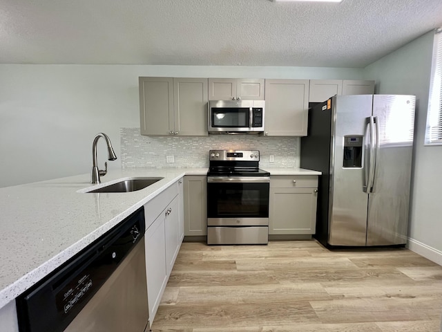 4345 Trevi Ct Unit 108, Lake Worth, FL 33467 - kitchen with appliances with stainless steel finishes, a sink, light wood-type flooring, gray cabinetry, and a textured ceiling