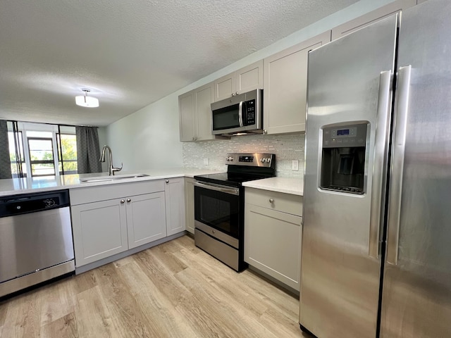 4345 Trevi Ct Unit 108, Lake Worth, FL 33467 - kitchen featuring stainless steel appliances, a sink, light wood-style floors, light countertops, and tasteful backsplash