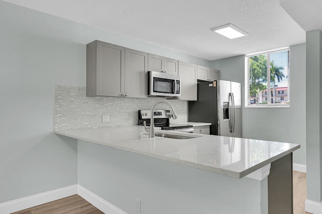 4345 Trevi Ct Unit 108, Lake Worth, FL 33467 - kitchen with stainless steel appliances, a peninsula, light wood-type flooring, gray cabinets, and backsplash