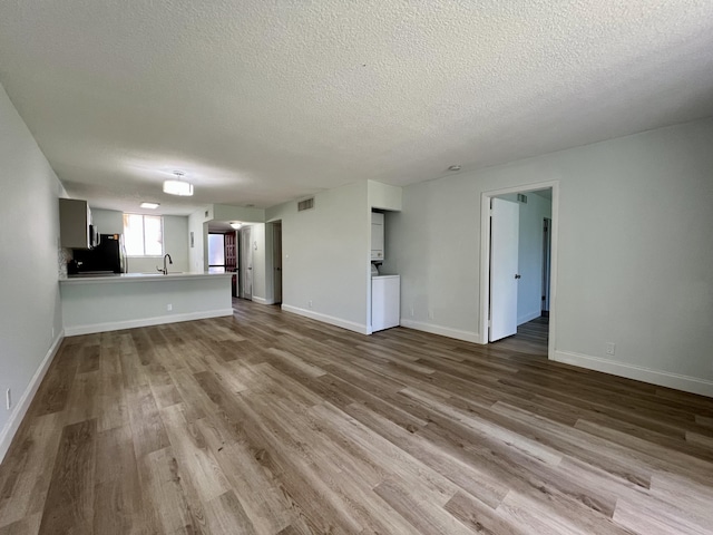 4345 Trevi Ct Unit 108, Lake Worth, FL 33467 - unfurnished living room with a textured ceiling, wood finished floors, a sink, and baseboards
