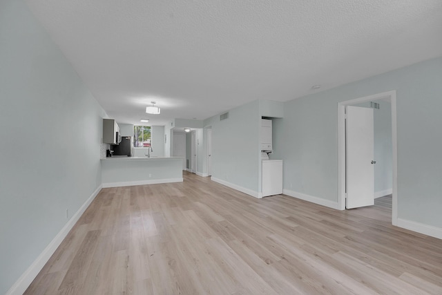 4345 Trevi Ct Unit 108, Lake Worth, FL 33467 - unfurnished living room with light wood finished floors, washer / dryer, and a textured ceiling