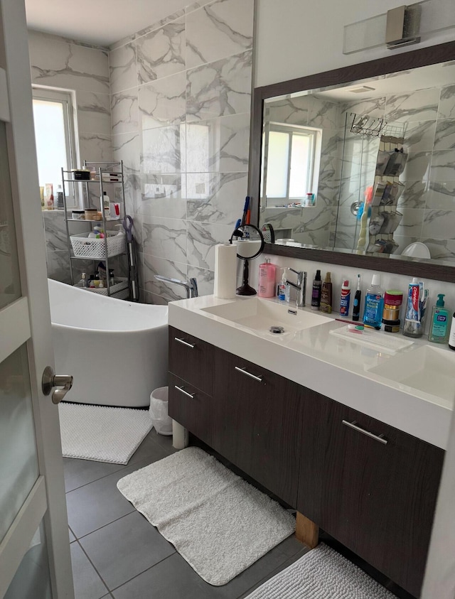6807 Via Regina Unit 1, Boca Raton, FL 33433 - bathroom with healthy amount of natural light, a freestanding tub, vanity, tile patterned floors, and tile walls