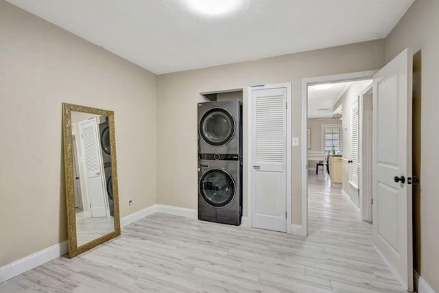 2940 SE Treasure Island Rd, Port Saint Lucie, FL 34952 - washroom featuring stacked washer / drying machine, light wood-style flooring, baseboards, and laundry area