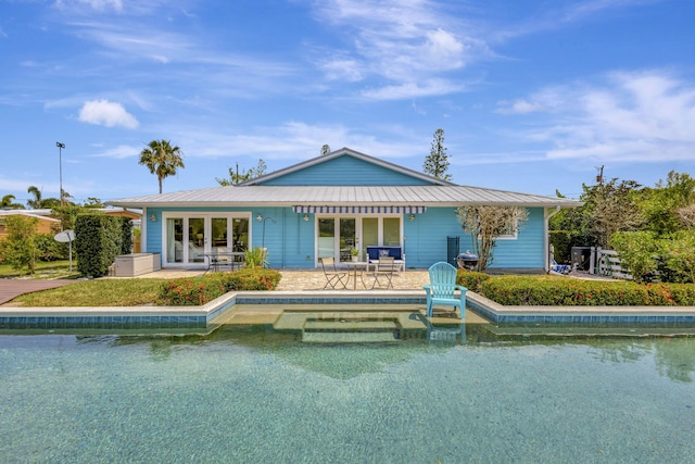 2940 SE Treasure Island Rd, Port Saint Lucie, FL 34952 - rear view of property with an outdoor pool, a standing seam roof, a patio, and metal roof