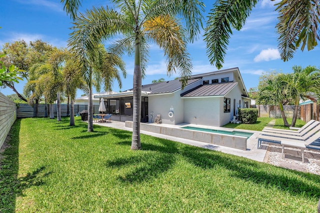 rear view of property with a lawn, a standing seam roof, a fenced in pool, stucco siding, and a fenced backyard