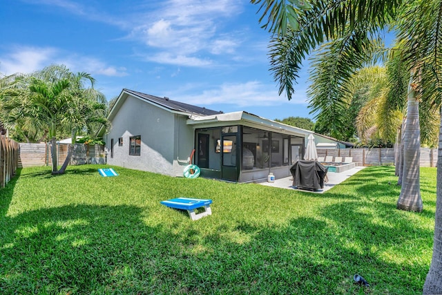 back of property with a lawn, stucco siding, a sunroom, and a fenced backyard