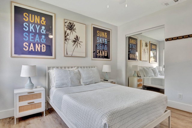 bedroom with baseboards, a closet, visible vents, and wood finished floors