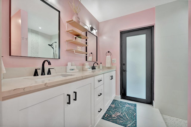 full bathroom featuring tile patterned flooring, tiled shower, double vanity, and a sink