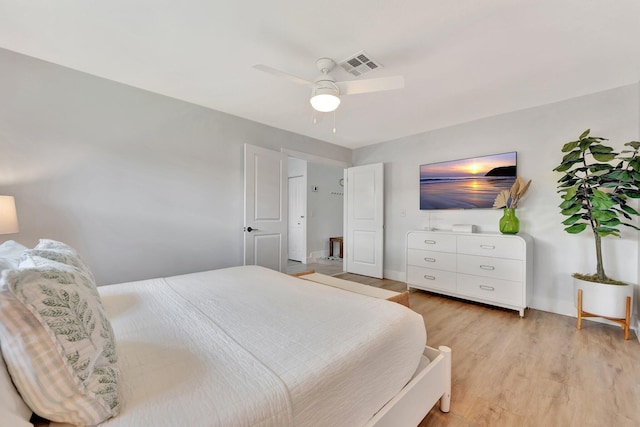 bedroom with light wood-style floors, visible vents, baseboards, and a ceiling fan