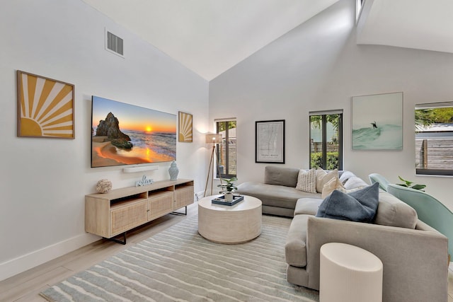 living room with visible vents, light wood-style flooring, baseboards, and high vaulted ceiling