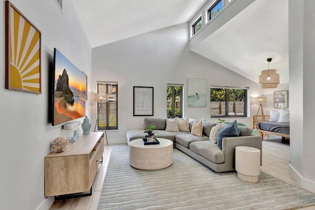 living room with light wood-style floors, baseboards, and high vaulted ceiling