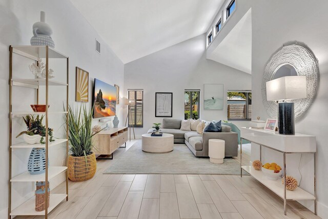 living area with high vaulted ceiling, visible vents, and wood finished floors