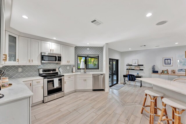 kitchen with white cabinets, visible vents, backsplash, light countertops, and appliances with stainless steel finishes