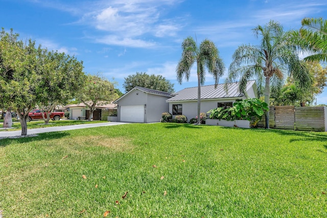 view of front facade featuring fence, metal roof, stucco siding, concrete driveway, and a front lawn