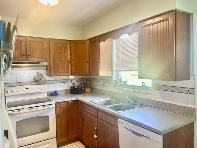7677 NW 90th Ct, Okeechobee, FL 34972 - kitchen featuring white appliances, under cabinet range hood, a sink, brown cabinetry, and backsplash