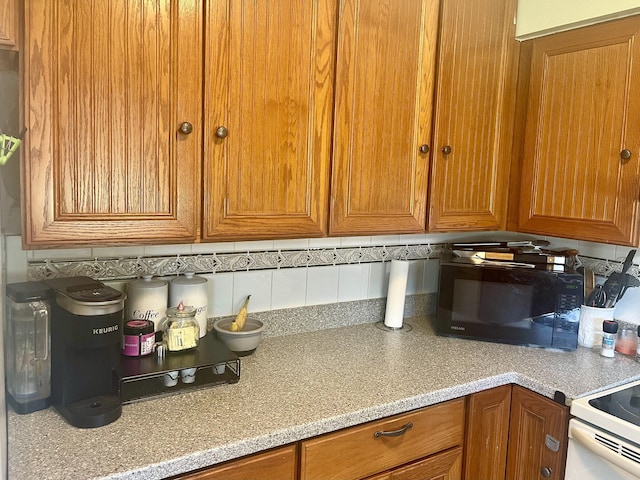 7677 NW 90th Ct, Okeechobee, FL 34972 - kitchen with black microwave, brown cabinets, and backsplash