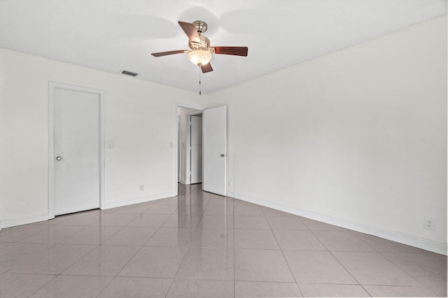 spare room featuring visible vents, a ceiling fan, baseboards, and tile patterned floors