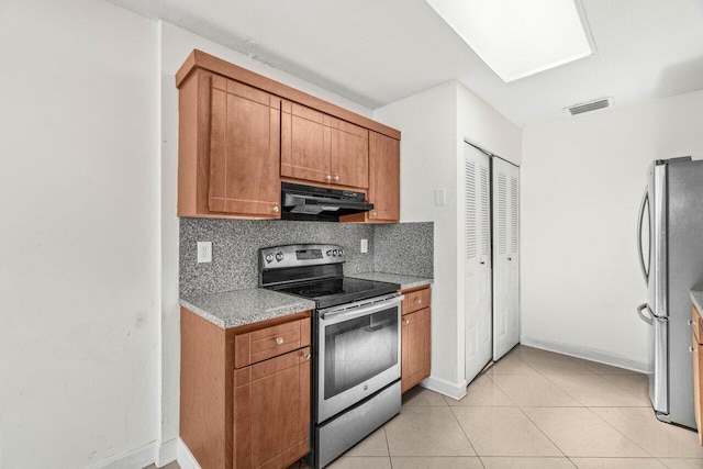 kitchen featuring decorative backsplash, visible vents, range hood, brown cabinets, and stainless steel appliances