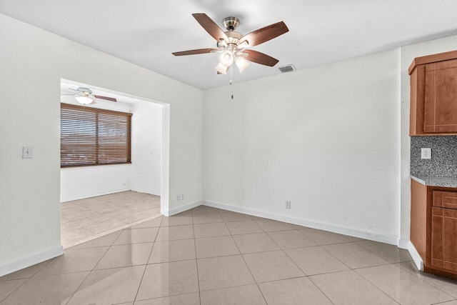 unfurnished room featuring a ceiling fan, baseboards, visible vents, and light tile patterned floors
