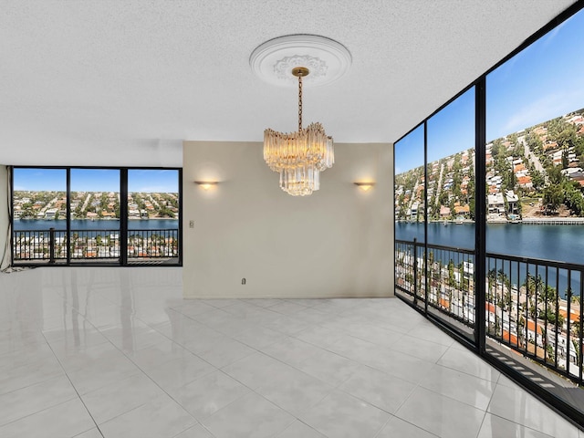 4740 S Ocean Blvd Unit 606, Highland Beach, FL 33487 - tiled empty room with a textured ceiling, a water view, a notable chandelier, and a wall of windows