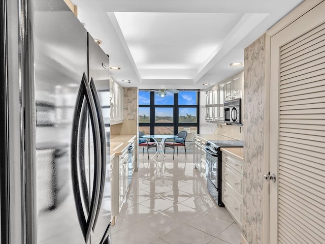 4740 S Ocean Blvd Unit 606, Highland Beach, FL 33487 - kitchen featuring light countertops, light tile patterned floors, a tray ceiling, floor to ceiling windows, and black appliances