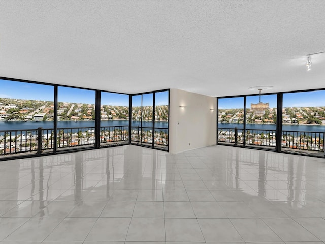 4740 S Ocean Blvd Unit 606, Highland Beach, FL 33487 - spare room with a water view, a textured ceiling, expansive windows, and tile patterned floors