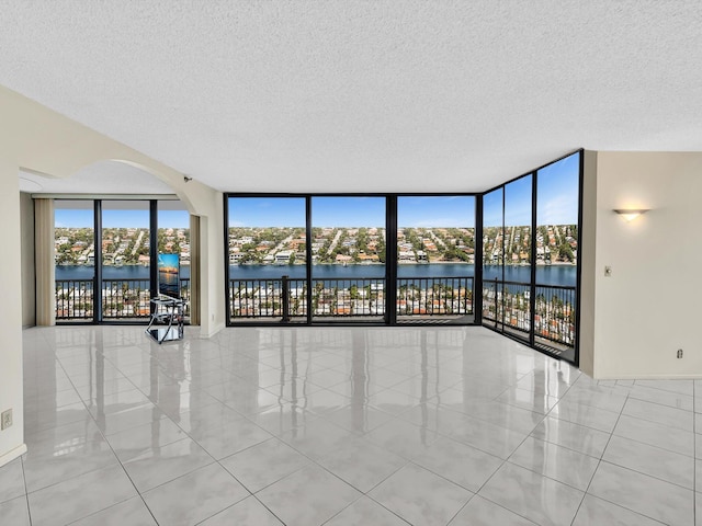 4740 S Ocean Blvd Unit 606, Highland Beach, FL 33487 - tiled spare room featuring arched walkways, floor to ceiling windows, and a textured ceiling