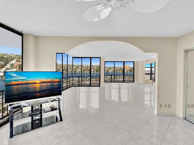 4740 S Ocean Blvd Unit 606, Highland Beach, FL 33487 - unfurnished living room featuring arched walkways, floor to ceiling windows, a textured ceiling, and tile patterned flooring