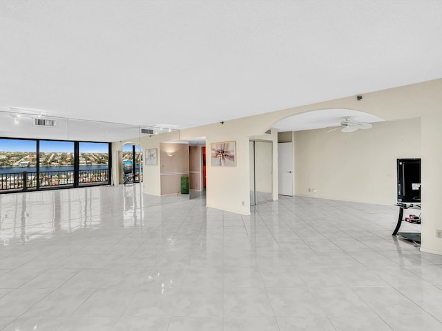 4740 S Ocean Blvd Unit 606, Highland Beach, FL 33487 - empty room featuring visible vents, ceiling fan, a water view, arched walkways, and light tile patterned floors