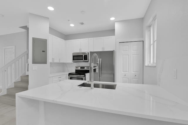 324 Bayfront Dr, Boynton Beach, FL 33435 - kitchen with white cabinets, stainless steel appliances, a peninsula, electric panel, and light stone countertops