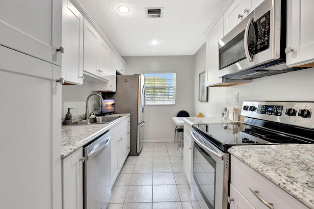 14699 Canalview C Dr Unit C, Delray Beach, FL 33484 - kitchen with stainless steel appliances, a sink, white cabinetry, a textured ceiling, and light tile patterned flooring