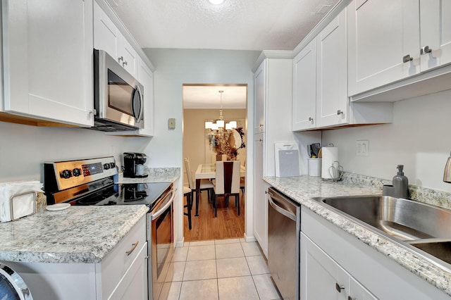 14699 Canalview C Dr Unit C, Delray Beach, FL 33484 - kitchen featuring stainless steel appliances, white cabinetry, a chandelier, light tile patterned floors, and a sink