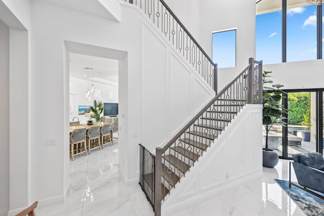 2560 NW 70th Blvd, Boca Raton, FL 33496 - staircase featuring a towering ceiling, marble finish floor, and baseboards