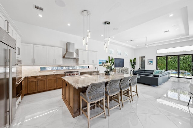 2560 NW 70th Blvd, Boca Raton, FL 33496 - kitchen featuring brown cabinets, backsplash, a sink, visible vents, and wall chimney exhaust hood
