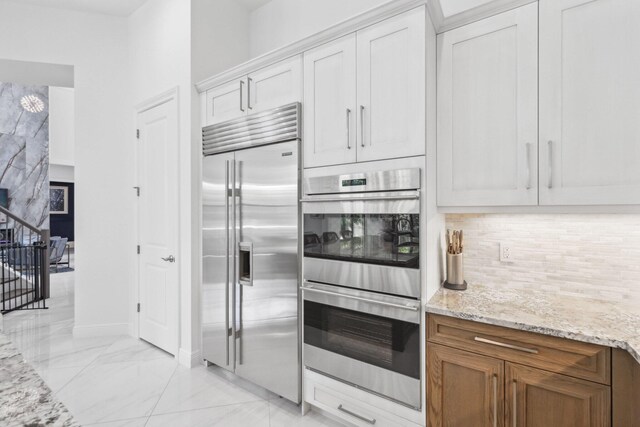 2560 NW 70th Blvd, Boca Raton, FL 33496 - kitchen featuring light stone countertops, stainless steel appliances, marble finish floor, backsplash, and baseboards