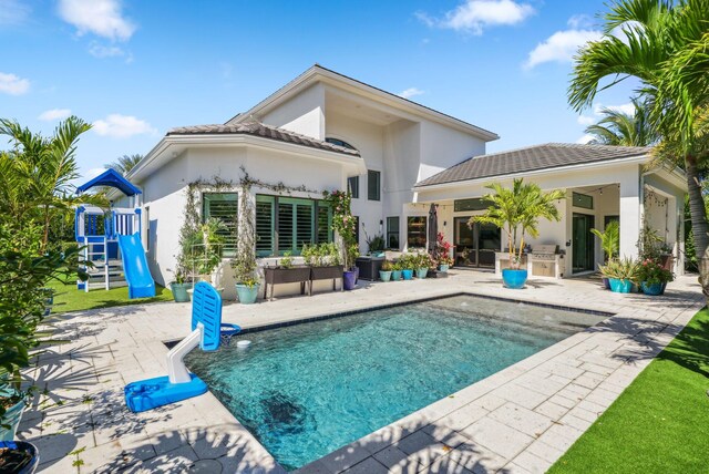 2560 NW 70th Blvd, Boca Raton, FL 33496 - rear view of property with stucco siding, an outdoor pool, a patio, and a playground