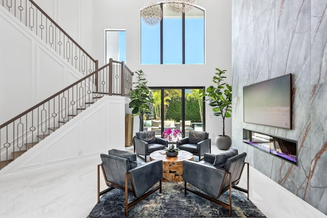 2560 NW 70th Blvd, Boca Raton, FL 33496 - living area featuring a fireplace, a towering ceiling, marble finish floor, and stairs