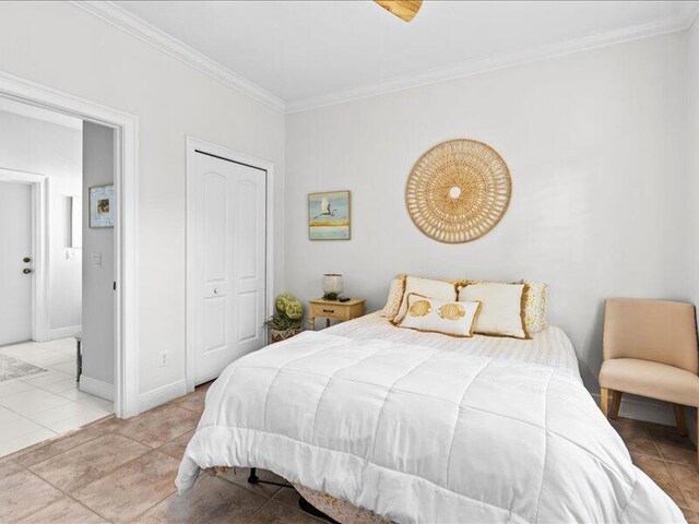bedroom featuring tile patterned floors, ornamental molding, baseboards, and a closet